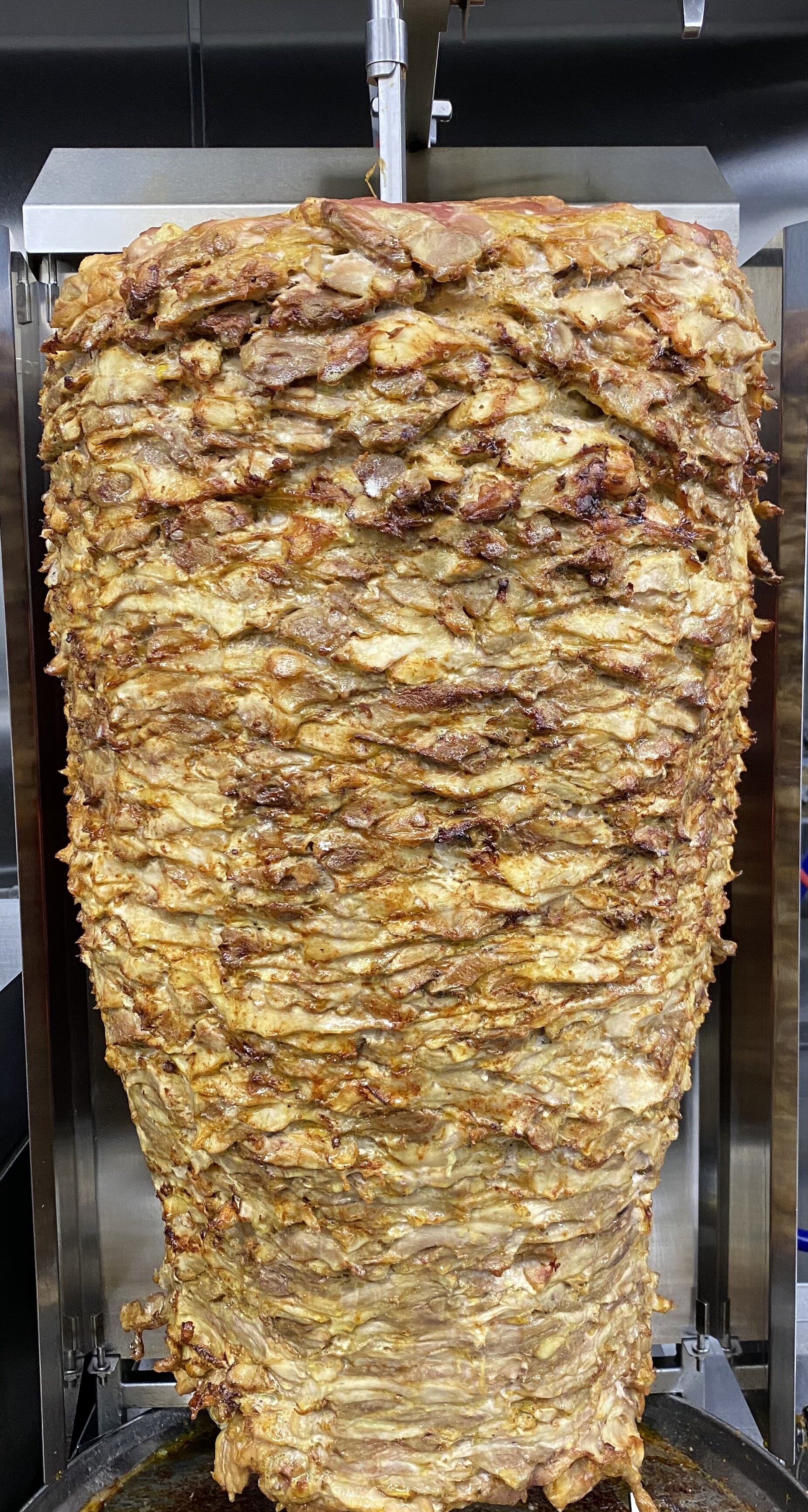 Char-edged chicken shawarma turning on the vertical spit at Double Taste